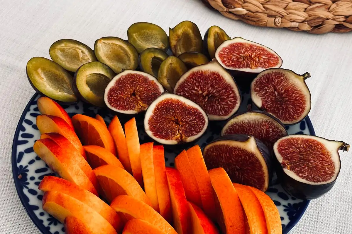 Fruta cortada en tiras y gajos servida en un plato, lista para comer con las manos.