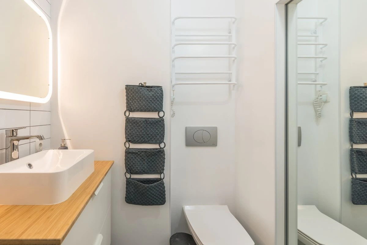 Baño luminoso y ordenado en tonos claros con cestas de almacenaje a la vista