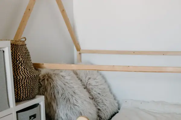 Cama Montessori tipo casita a ras de suelo con estructura de madera en una habitacion infantil