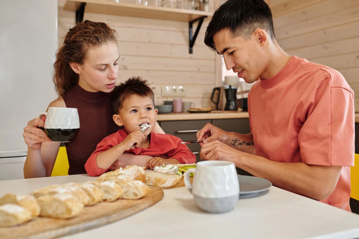 Madre, padre y niño pequeño desayunando juntos a la mesa de la cocina.