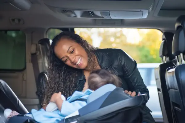 Madre sonriendo a su bebé en la silla de coche dentro del vehículo