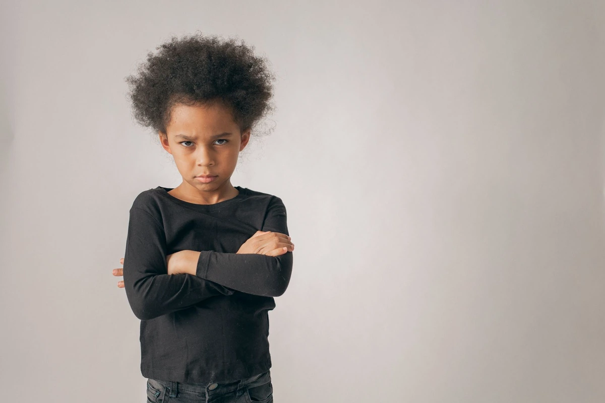 Niño con los brazos cruzados y el ceño fruncido, enfadado y frustrado