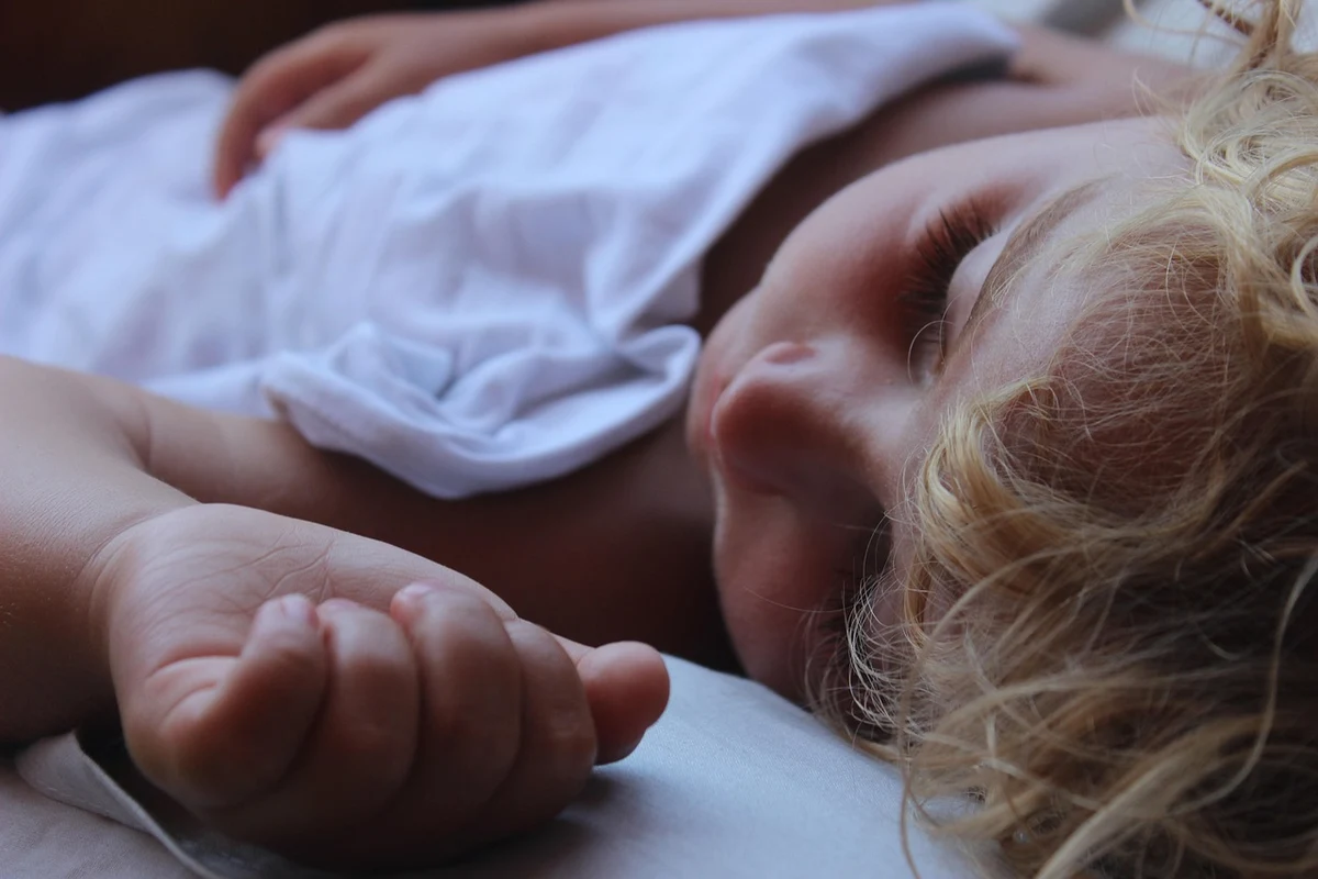 Niño pequeño durmiendo la siesta en la cama con luz suave de día