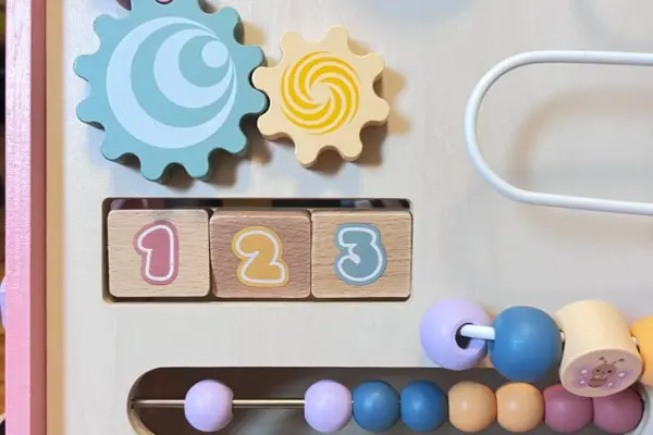 Panel de un juguete de actividades de madera con engranajes, bloques numerados y cuentas de colores