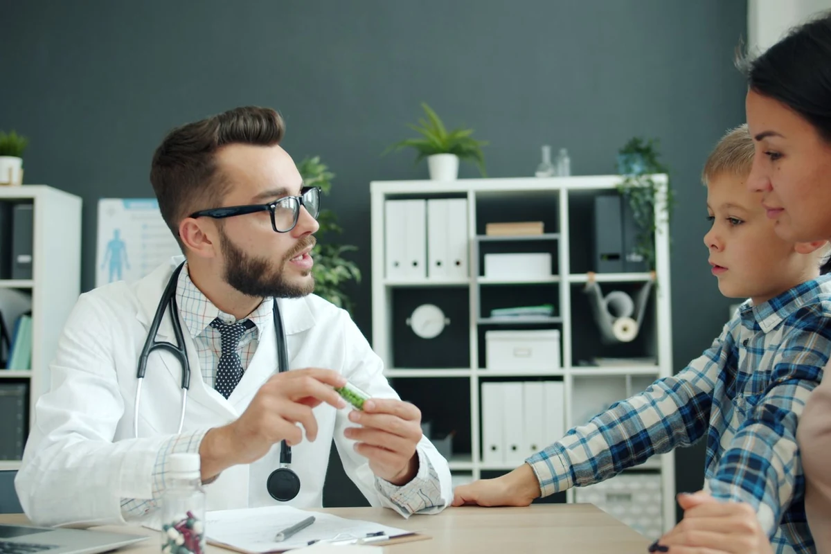 Pediatra conversando con una madre y su hijo en la consulta