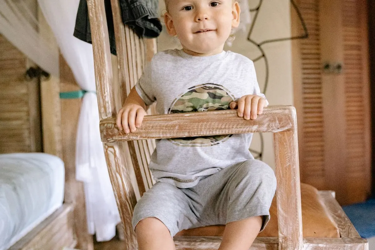 Niño pequeño sonriente en su habitación con un orinal blanco en el suelo.