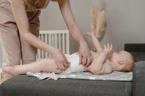 Madre cambiando el pañal a su bebé sobre un cambiador