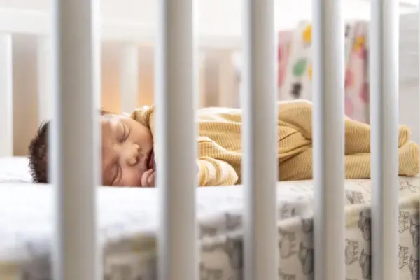 Bebé dormido en su cuna visto entre los barrotes